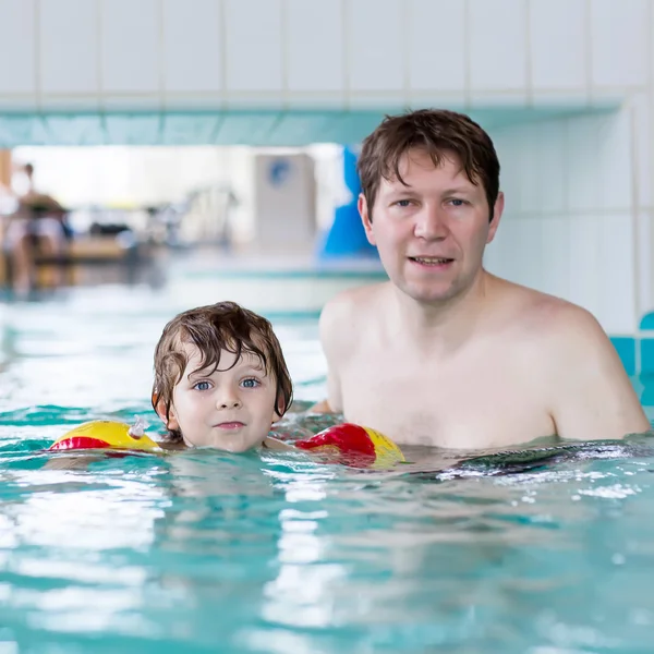 Papá joven enseñando a su pequeño hijo a nadar en el interior —  Fotos de Stock