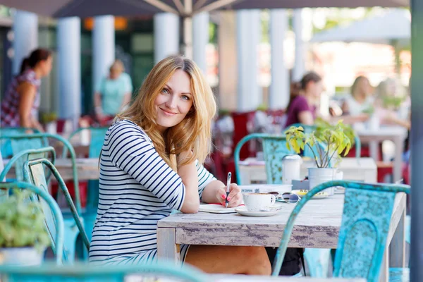 Femme buvant du café et écrivant des notes dans le café — Photo