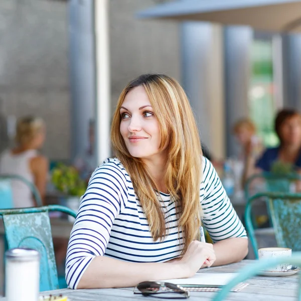 Женщина пьет кофе и пишет заметки в кафе Лицензионные Стоковые Изображения