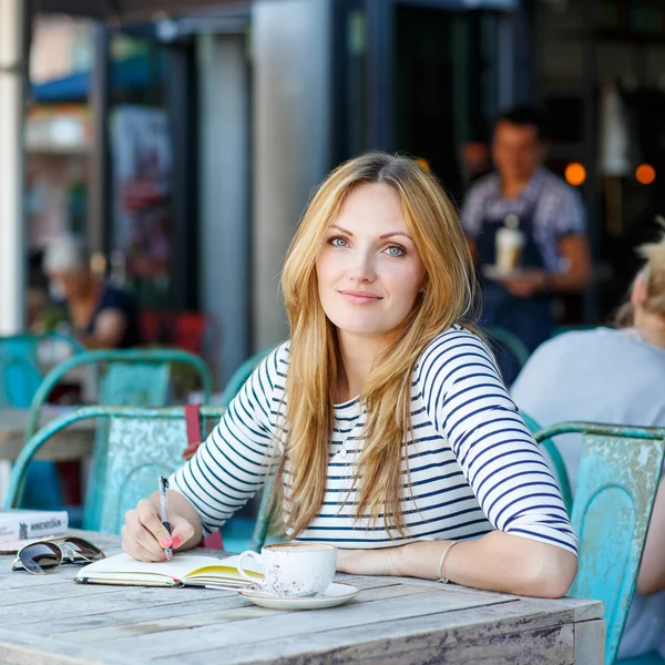 Mujer tomando café y escribiendo notas en la cafetería —  Fotos de Stock