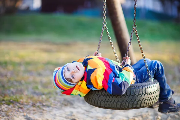 Malé dítě chlapec houpání na hřišti venku — Stock fotografie
