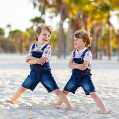 İki küçük çocuk tropik sahilde eğleniyor.