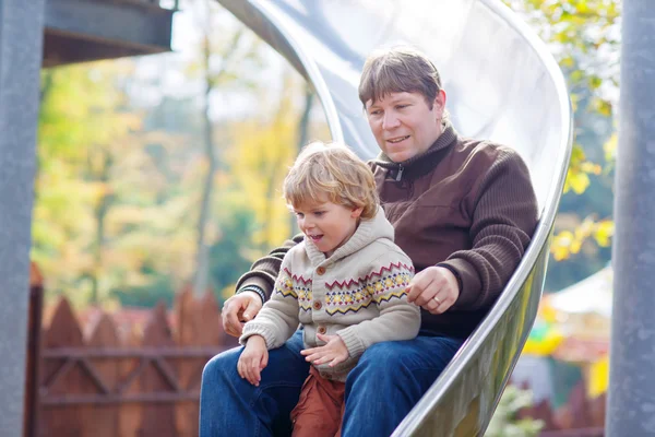 Pai e menino deslizando no playground — Fotografia de Stock