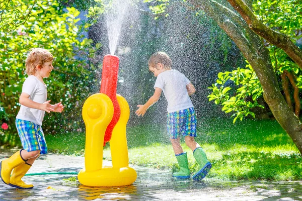 Two little kids playing with water sprinkler — Stock Photo, Image