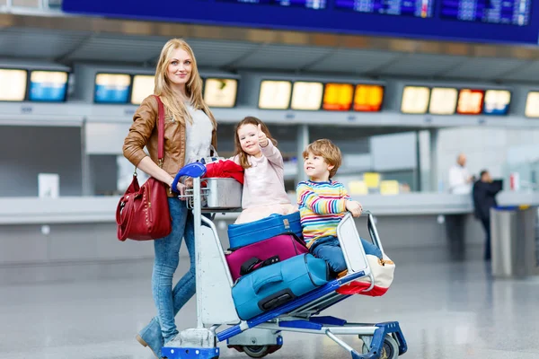 Niña y niño y madre joven con maletas en el aeropuerto — Foto de Stock