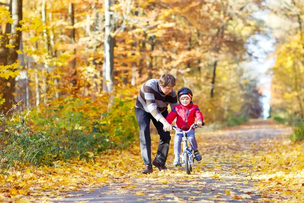 Маленький мальчик и отец с велосипедом в осеннем лесу — стоковое фото