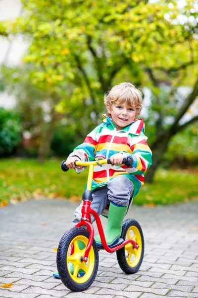 Bambino ragazzo guida in bicicletta il giorno di pioggia all'aperto — Foto Stock