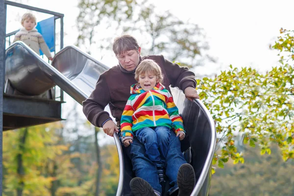 Pai e menino deslizando no playground — Fotografia de Stock