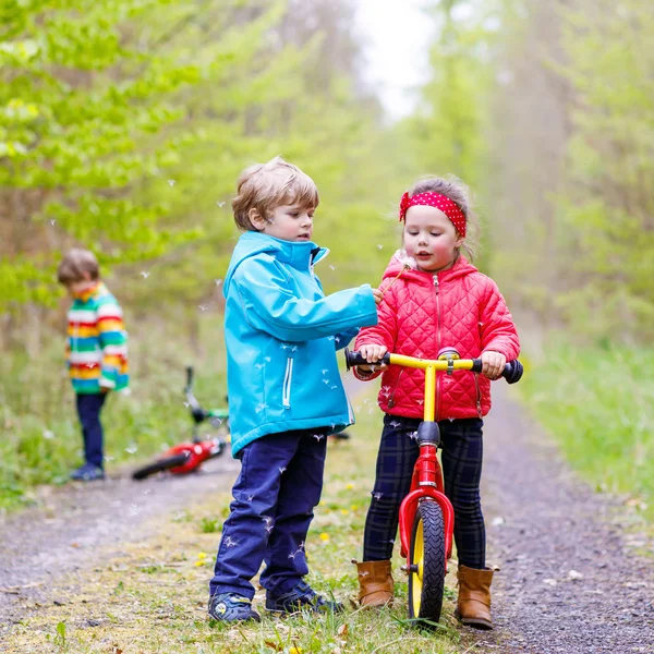 Boy and girl with bicycles and blowing dandelion — Stock Photo, Image