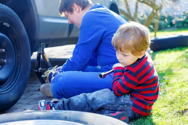 キッド少年と彼の父親は、車のホイールを変更します。 — ストック写真