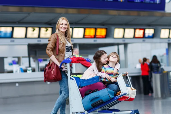 Lille jente og gutt og ung mor med kofferter på flyplassen – stockfoto