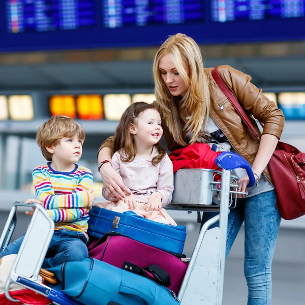 Niña y niño y madre joven con maletas en el aeropuerto — Foto de Stock