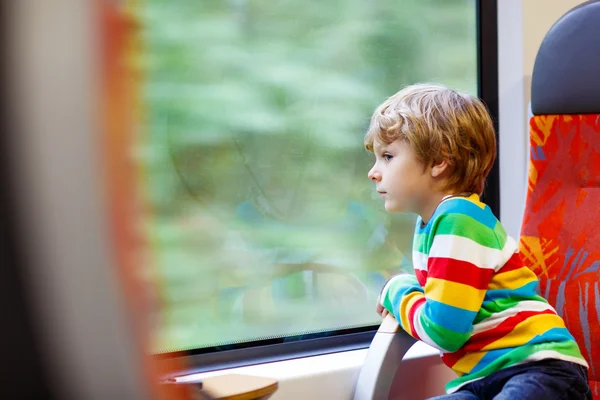 Little boy sitting in train and going on vacations — Stock fotografie