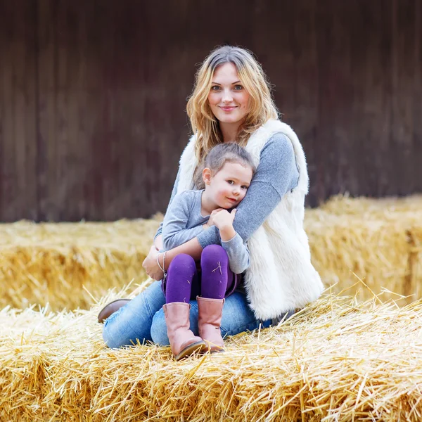 Glad tjej och mamma att ha kul med hö på en gård — Stockfoto