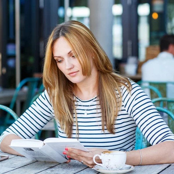Woman drinking coffee and reading book in cafe — Stock Photo, Image