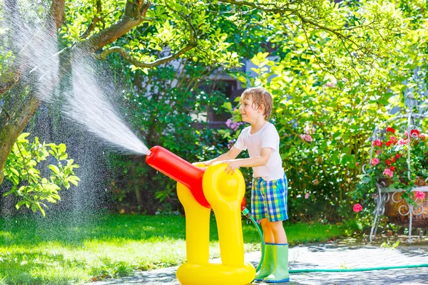 Niño jugando con una manguera de jardín y agua — Foto de Stock