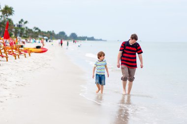 Küçük çocuk çocuk ve babası kabukları toplama ile eğleniyor