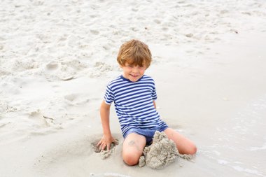 Küçük çocuk çocuk kumdan kaleler inşa ile eğleniyor