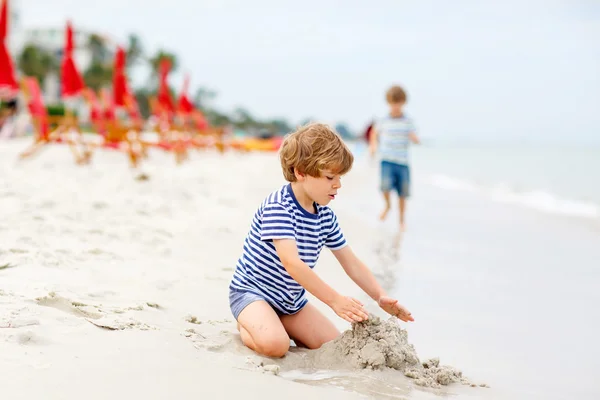 Malý kluk kluk baví s budování hrady z písku — Stock fotografie