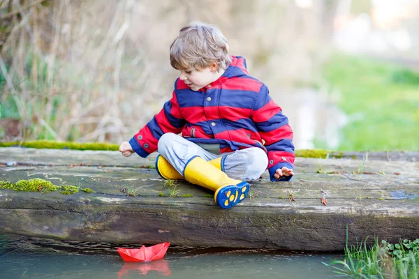 Menino brincando com barco de papel por poça — Fotografia de Stock