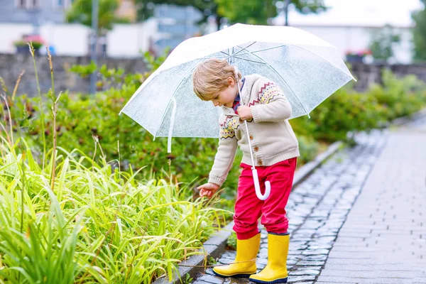 Mały chłopiec blond dziecko chodzenie z wielkim parasolem na zewnątrz — Zdjęcie stockowe