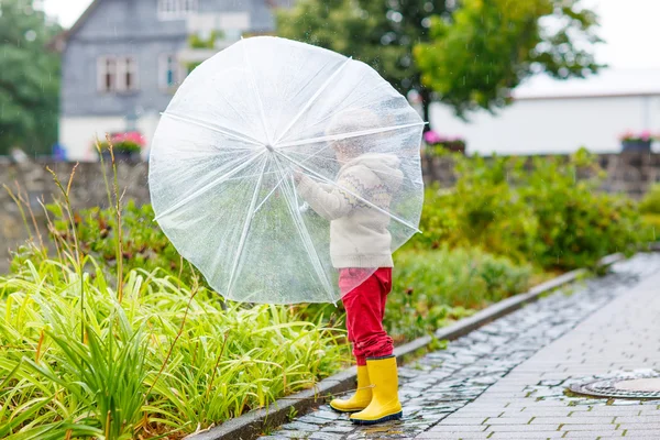 Little blond kid boy walking with big umbrella outdoors — Stock Photo, Image