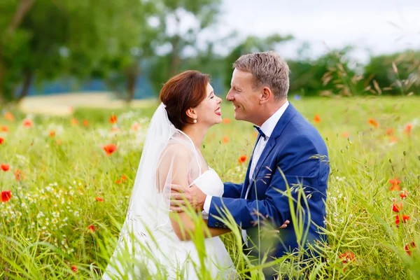 Счастливая свадебная пара в розовом маковом поле — стоковое фото