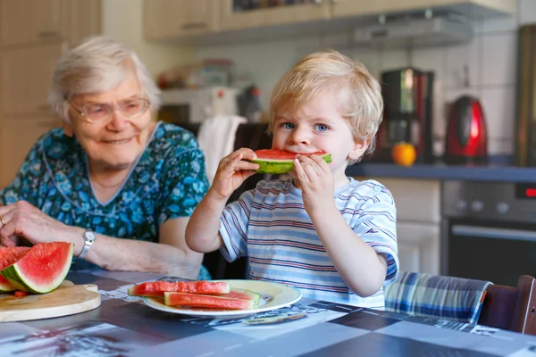 Little toddler boy and great grandmother eating watermelon — Stock Photo, Image