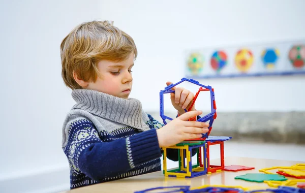 Маленький мальчик строит геометрические фигурки из пластиковых блоков — стоковое фото