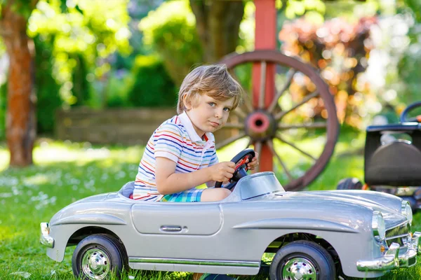 Kid boy dirigindo com grande carro de brinquedo ao ar livre — Fotografia de Stock