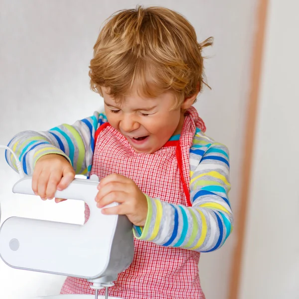 Rolig blond liten pojke baka äppelkaka inomhus — Stockfoto
