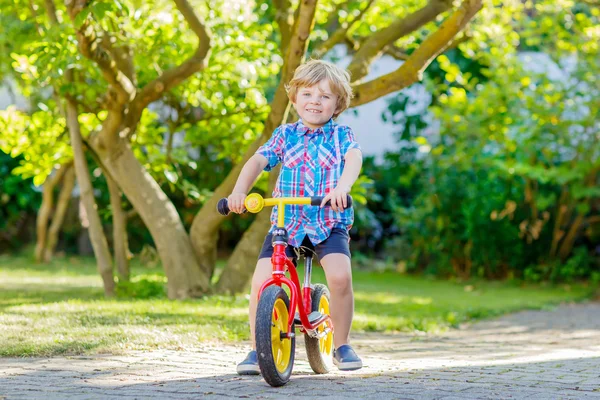 Kid boy driving tricycle or bicycle in garden — Stock Photo, Image