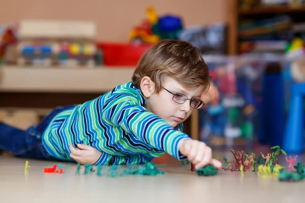 Garoto brincando com soldados de brinquedo dentro de casa no berçário — Fotografia de Stock