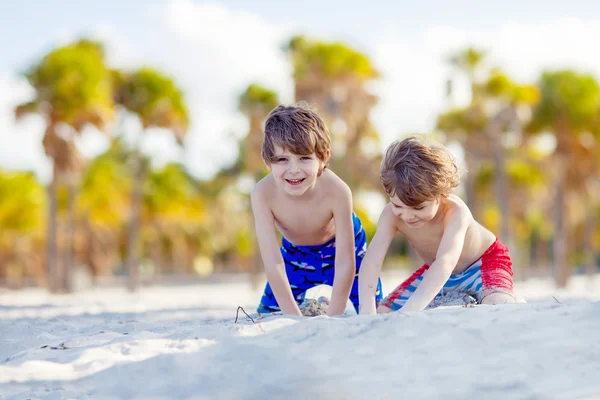 Двоє маленьких хлопчиків розважаються на тропічному пляжі — стокове фото