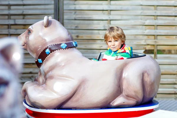 Niño en el carrusel en el parque de atracciones — Foto de Stock