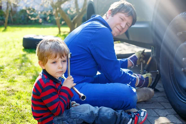 Jongen-jongetje en zijn vader wijzigen wiel op auto — Stockfoto