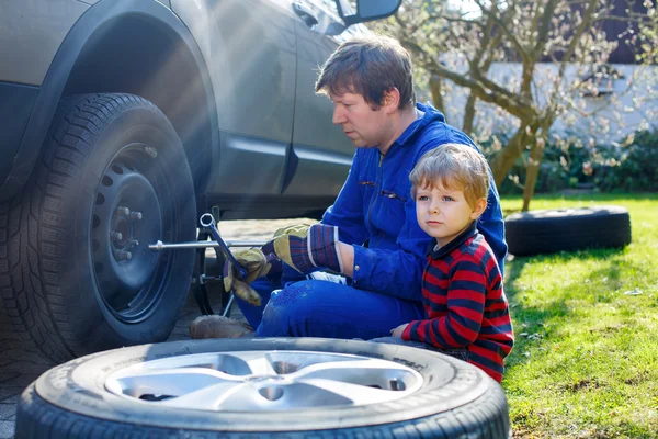 Mały chłopiec dziecko i jego ojciec, zmiana koła w samochodzie — Zdjęcie stockowe