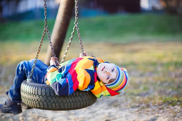 Petit garçon balançant sur une aire de jeux à l'extérieur — Photo