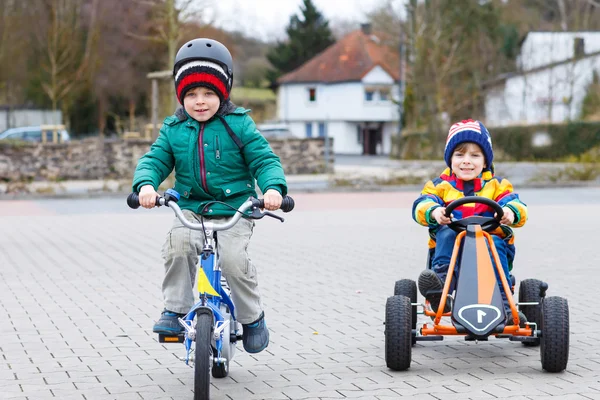 Två små pojkar leker med racerbil och cykel — Stockfoto