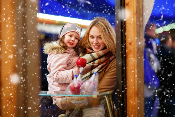 Mother and little kid girl eating crystalized apple on Christmas — Stock Photo, Image