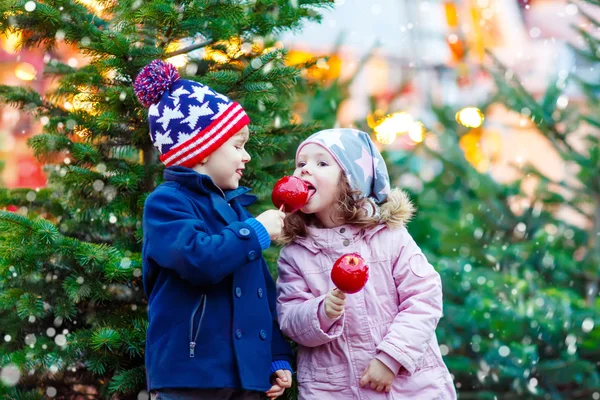 Two little kids eating crystalized apple on Christmas market — Stock Photo, Image