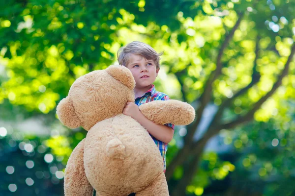 Menino brincando com grande urso de pelúcia, ao ar livre . — Fotografia de Stock