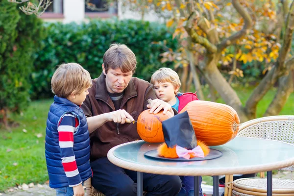 Father and two little kid boys making halloween pumpkin — Stock Photo, Image