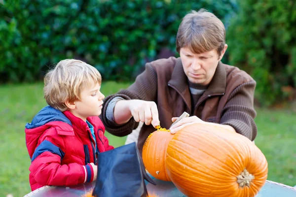 Otec a malý kluk dělají Halloweenskou dýni — Stock fotografie