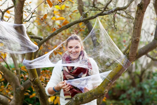 Woman decorating home garden for halloween with spider web — Stok fotoğraf