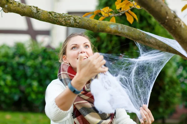 Mujer decorando jardín casero para Halloween con tela de araña —  Fotos de Stock