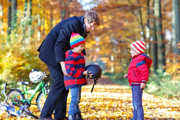 Двоє маленьких хлопчиків і батько з велосипедами в осінньому парку — стокове фото