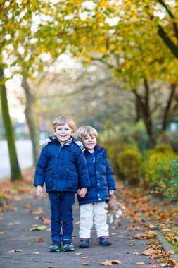 iki çocuk erkek sonbahar parkta birlikte yürüyüş