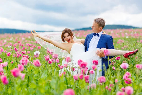 Happy wedding couple in pink poppy field — Stock Photo, Image