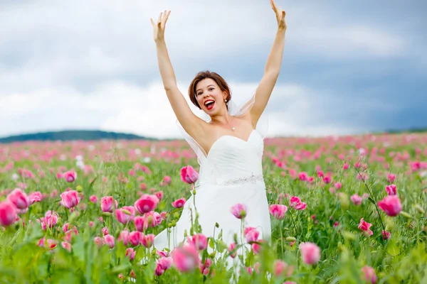 Szczęśliwa Panna Młoda w białej sukni, zabawy w pole kwiat maku — Zdjęcie stockowe